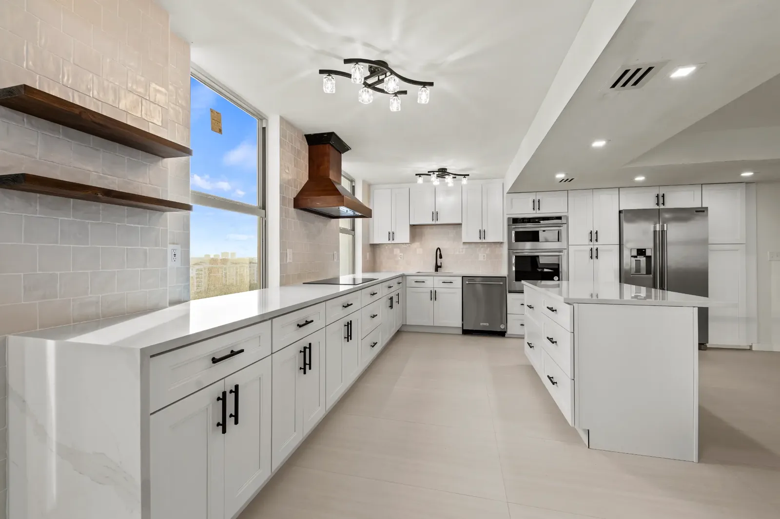 Finished white kitchen renovation with custom cabinetry, stone counters, and large windows